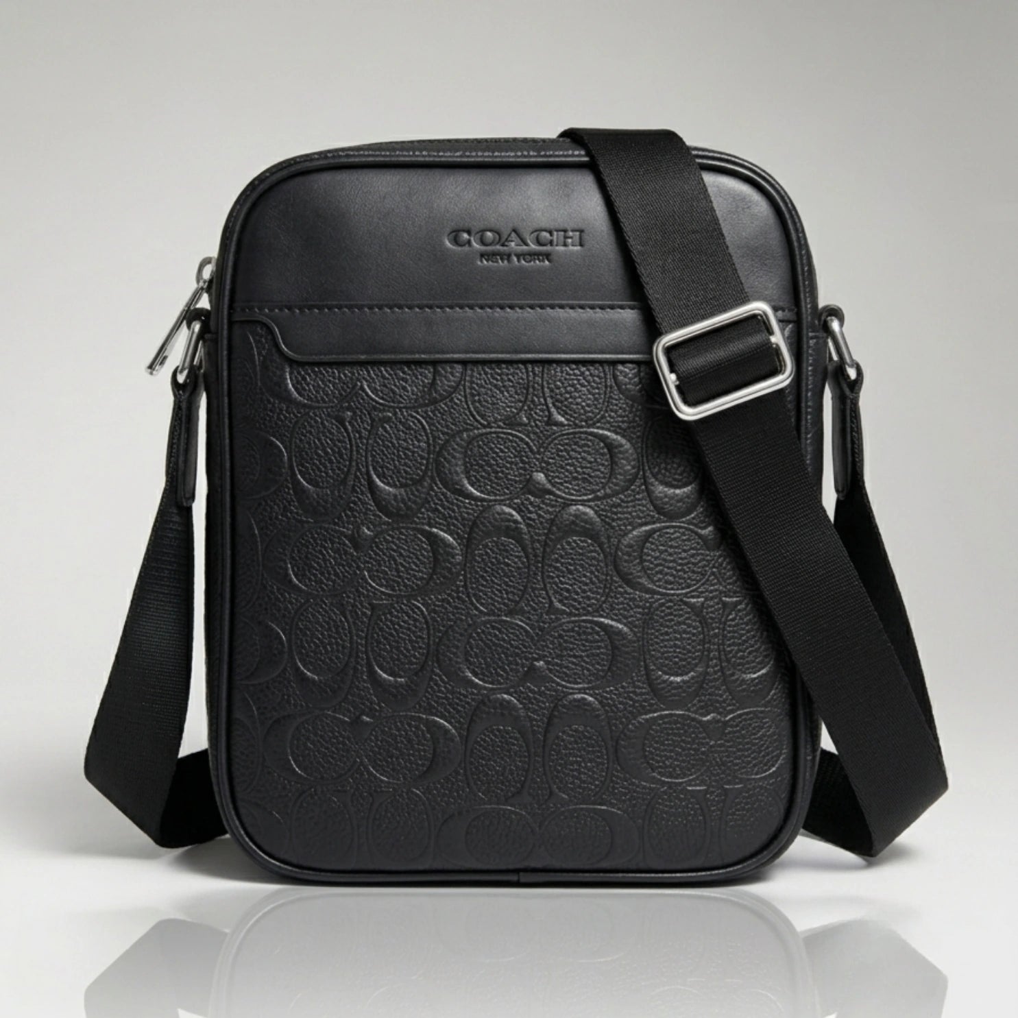 Coach black signature debossed leather crossbody bag with an adjustable strap.