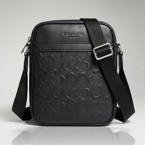 Coach black signature debossed leather crossbody bag with an adjustable strap.