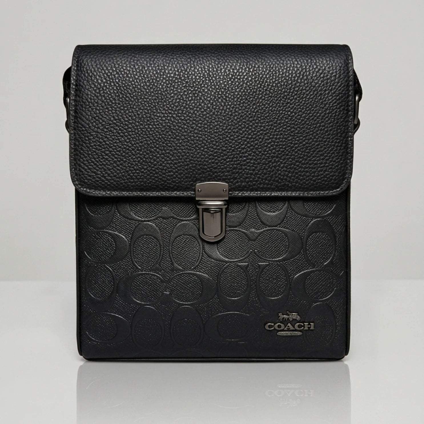 Coach black signature embossed flap messenger bag with metal push lock closure.