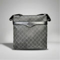 Gucci GG Supreme black canvas flat crossbody bag with leather trim and silver Double G emblem.
