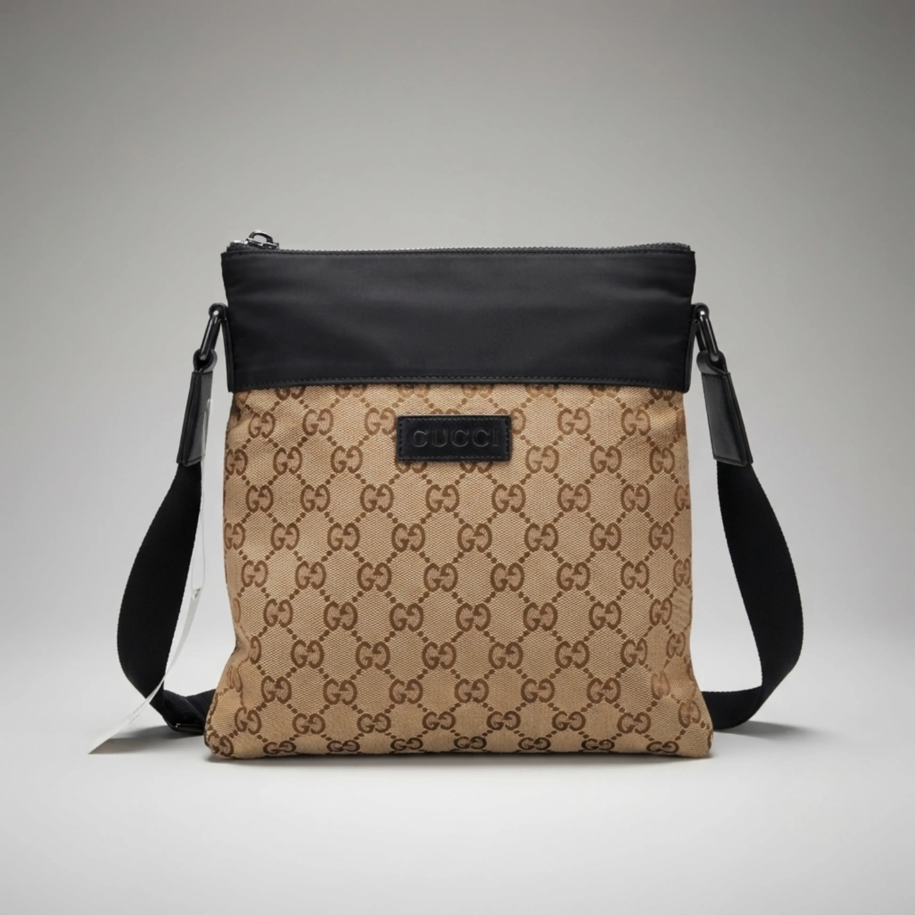 Gucci beige GG canvas flat crossbody bag with black top trim and leather logo patch.